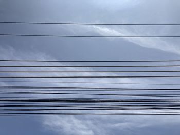 Low angle view of power cables against sky