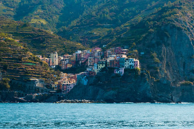 Scenic view of sea by mountain against sky