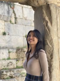 Young woman standing against stone wall