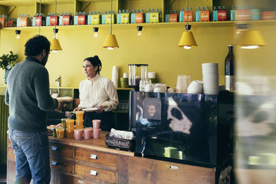 Waitress serving croissant while looking at customer in cafe