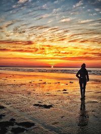 Silhouette man standing on beach against sky during sunset