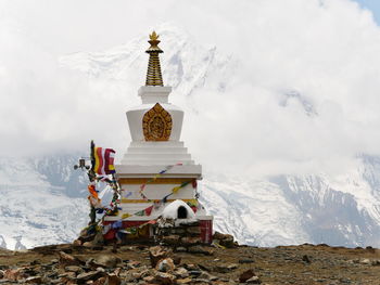 Traditional windmill on snowcapped mountain against sky