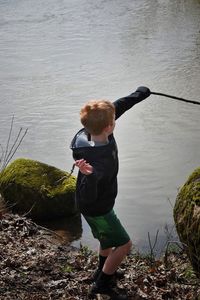 High angle view of boy throwing twig in lake