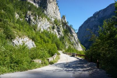 Road amidst trees and mountains against sky