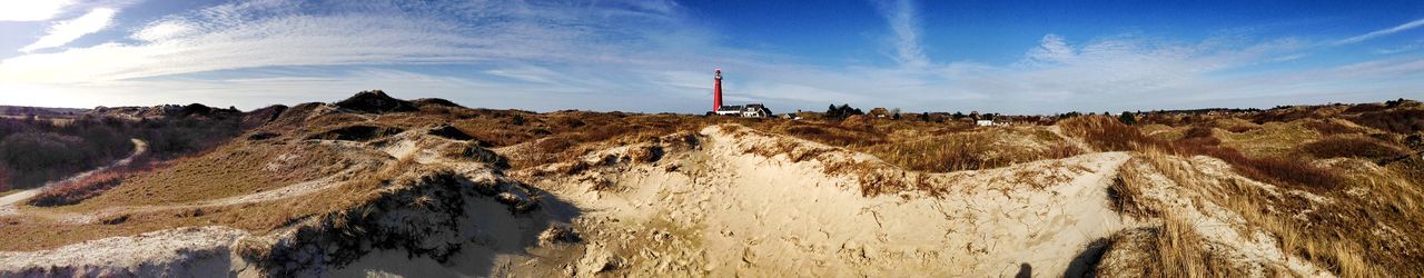 sky, tranquility, lighthouse, landscape, tranquil scene, scenics, guidance, nature, beauty in nature, built structure, architecture, blue, cloud - sky, building exterior, panoramic, water, day, sand, direction, cloud