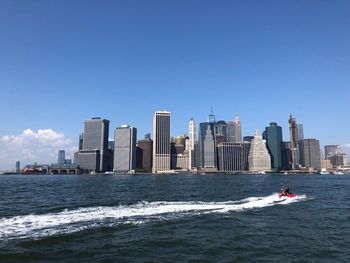 Modern buildings by sea against sky in city