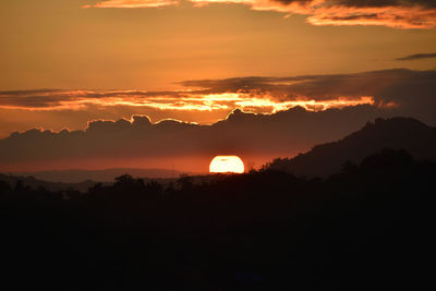 Scenic view of dramatic sky over silhouette landscape during sunset