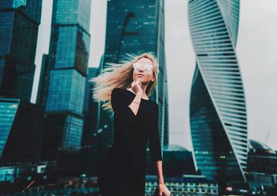 Young woman standing against buildings in city