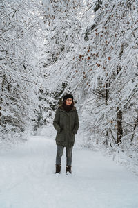Portrait of woman standing amidst trees during winter
