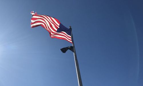 Low angle view of flag against blue sky