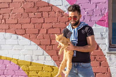 Young man with dog standing against wall