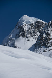 Snowcapped mountains against clear blue sky