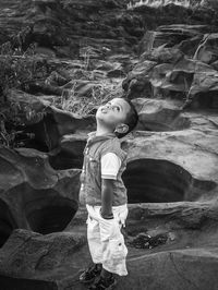 Cute boy looking up while standing on rocks 