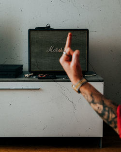 Midsection of man using mobile phone on table against wall