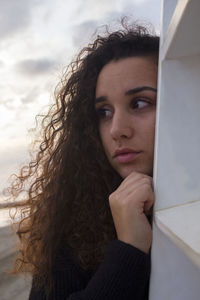 Close-up of beautiful young woman with curly hair looking away