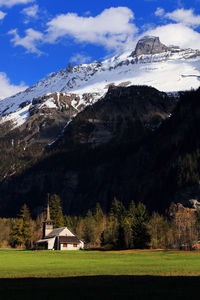 Church on field against snowy mountains