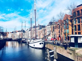 Sailboats moored on canal by buildings in city against sky