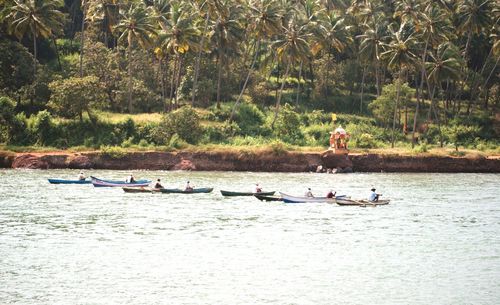 People in boat on river against trees