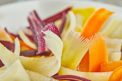 Slices of carrots of three colors, cut into strips in glass bowl