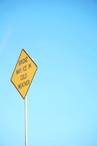 Close-up of road sign against blue sky