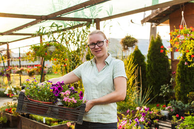 Woman standing by plants at greenhouse