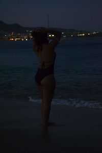 Rear view of woman standing on beach at night