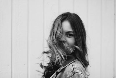 Portrait of young woman standing against wall