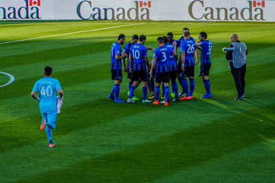 Rear view of people standing on soccer field