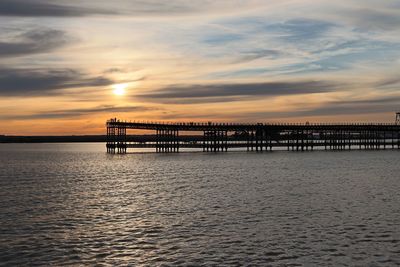 Silhouette pier over sea against sky during sunset