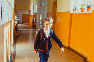 Full length of happy boy standing in building