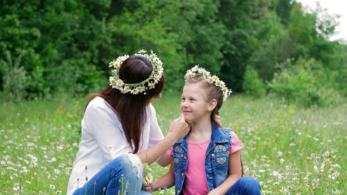 Amidst a chamomile lawn, a young woman, a brunette and a girl of seven, mother and daughter