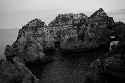 Rock formations by sea against sky