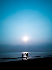 Silhouette people on beach against sky during sunset