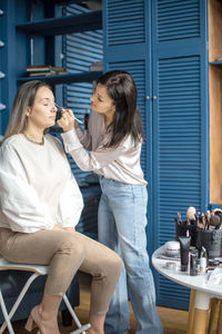 Beautician applying make up on woman face