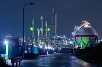 Illuminated factory against sky at night