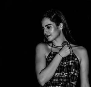 Portrait of smiling woman against black background