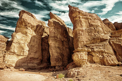 Low angle view of rock formation against cloudy sky