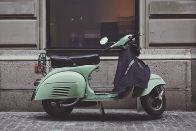 Scooter parked against building