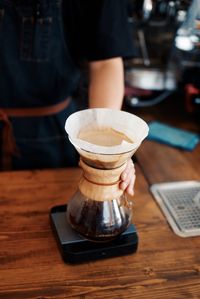 Midsection of man holding coffee cup on table