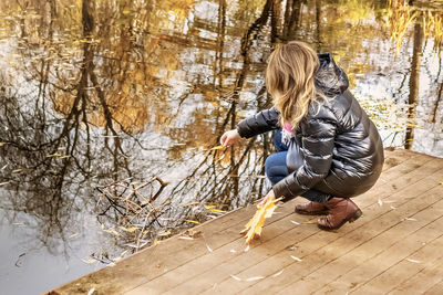 A young woman on the shore of a pond in an autumn park.
