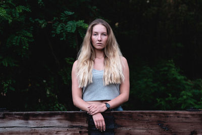 Portrait of beautiful young woman sitting against trees