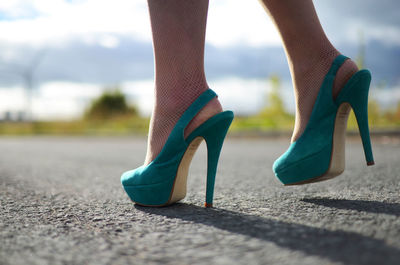 Low section of woman wearing high heels standing on road