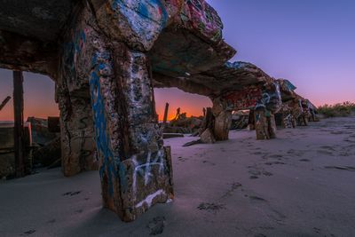 Damaged rock formation on land against sky during sunset