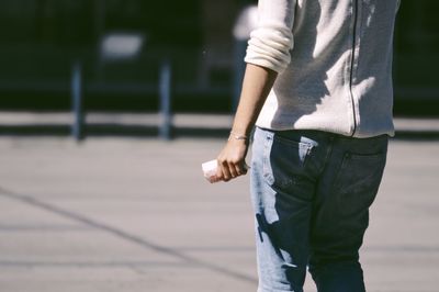 Midsection of man with umbrella walking in city