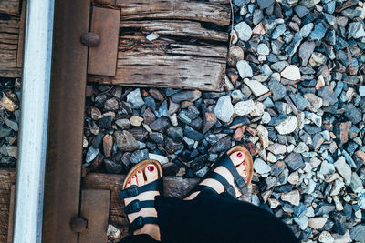 Low section of woman standing on railroad tie by track