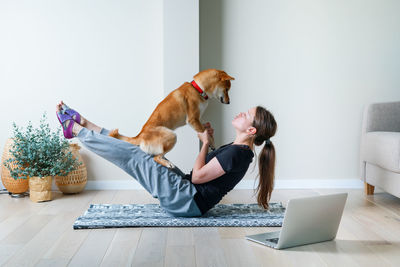 Young woman in yoga position balancing with her dog. home online training with a pet. doga yoga