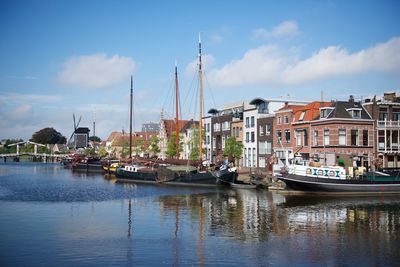 Boats moored at harbor against sky in city