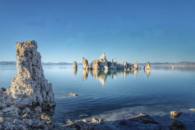 Group of people on rock by sea against clear sky