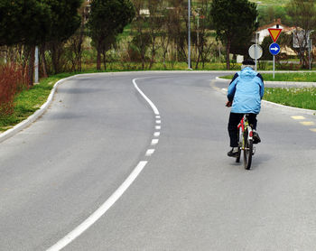 Rear view of man riding bicycle on road