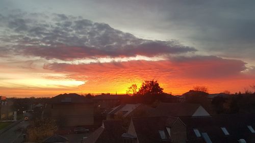 Houses in town against sky during sunset